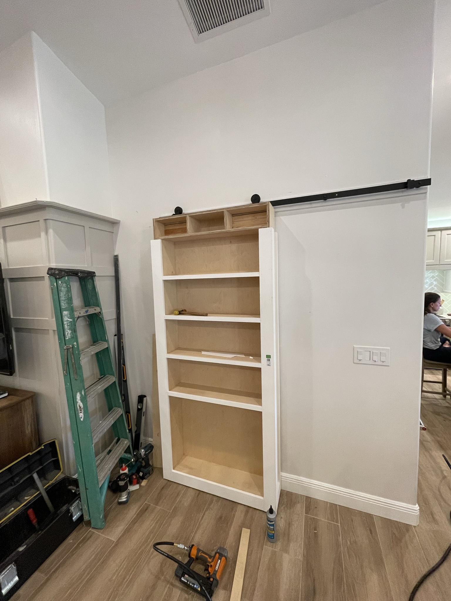 Photo of the installed sliding bookshelf custom-built by ArkWorks, designed as a room divider between the laundry area and living space